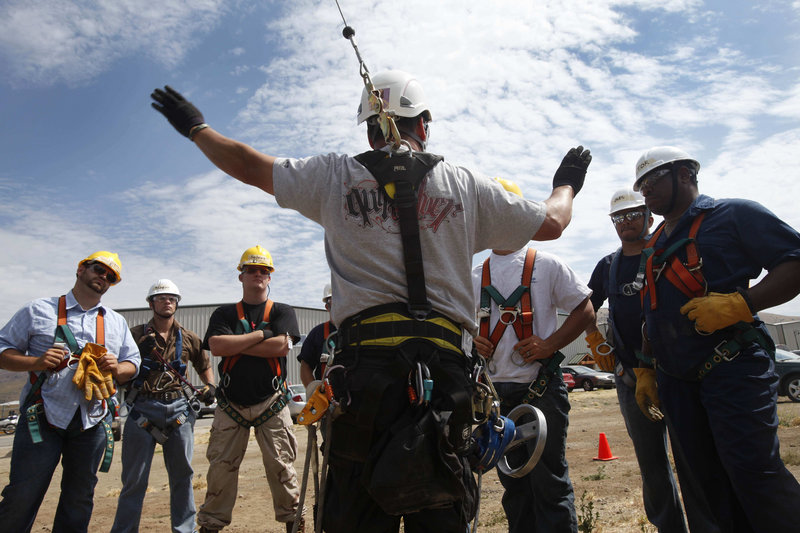 Wind and oil industry safety instructor Carl Mosby talks to his students, most of whom are military veterans, about their next exercise: rappelling from a 30-foot mobile training tower in Tehachapi, Calif.