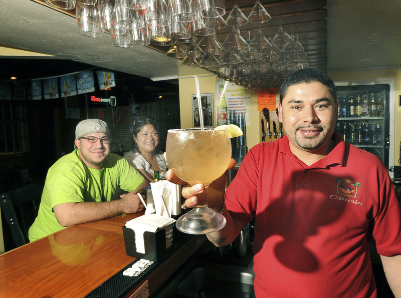 Bartender Gama Chavez serves a margarita to Adam Smith and Thea Hernandez at Cancun in Biddeford. Mix-and-match food platters complement Cancun's big drinks.