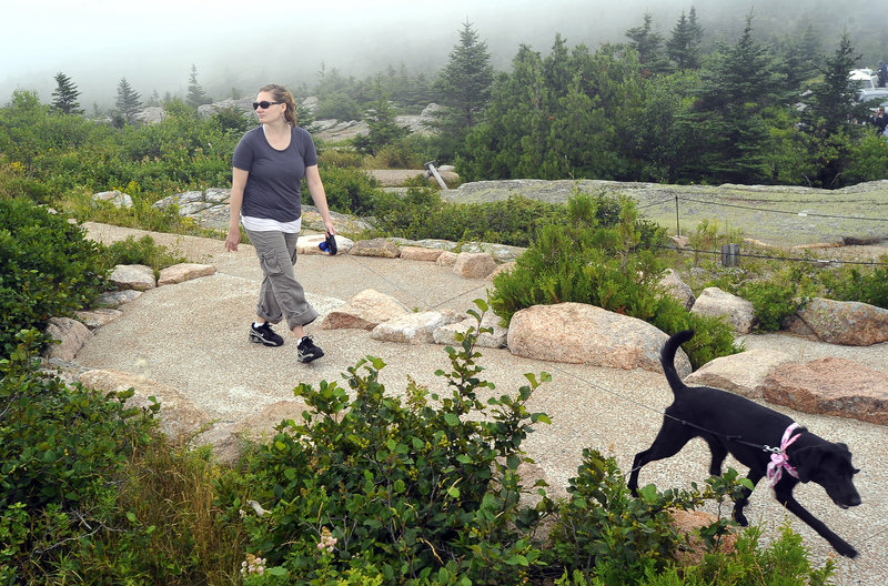 Heather Stark, a visitor from Pennsylvania, walks with her dog Dora on Cadillac Mountain.