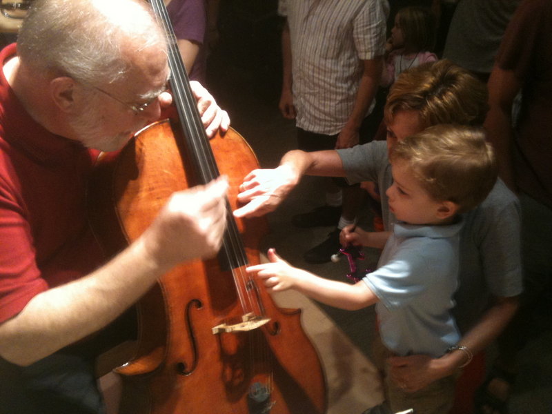 Cellist Marc Johnson introduces a toddler to string instruments.