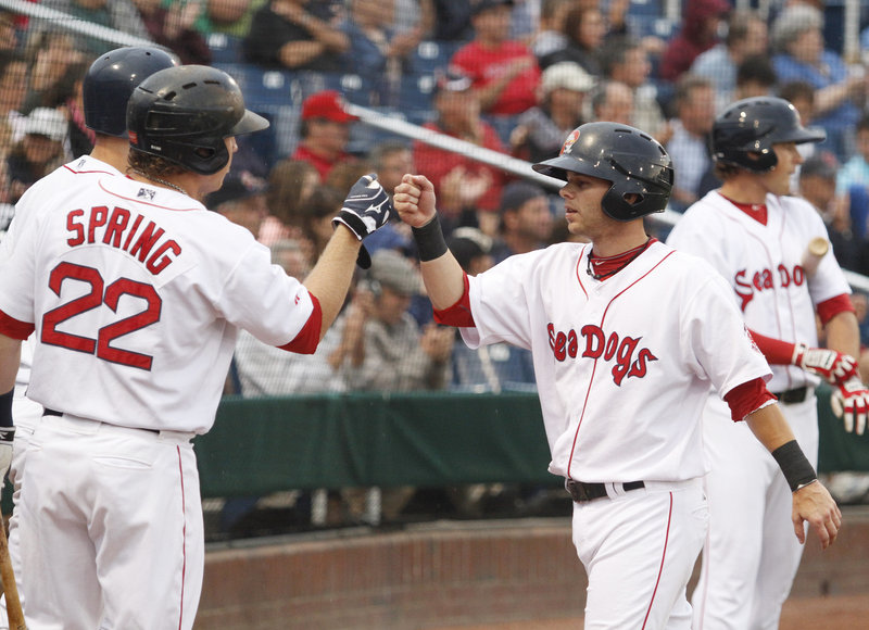 Ryan Khoury of the Portland Sea Dogs is greeted by teammates Tuesday night after scoring a first-inning run on a triple by Mark Wagner at Hadlock Field. Portland went on to a 9-2 victory against the Akron Aeros.