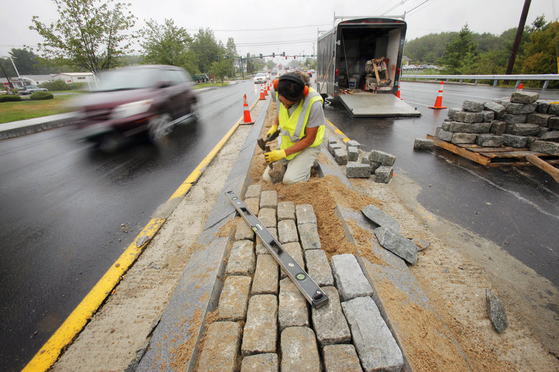 Frank Navarro places landscaping cobbles into the median near the intersection of Route 1 and Haigis Parkway Wednesday in Scarborough, one of two projects aimed at easing bottlenecks on Route 1. So far, local reaction to the work has been mixed.