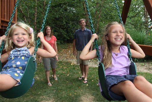 Anna, 8, right, and Sophia, 5, left, get pushed on their swing set by their parents, Maria and John Seyerle, in the backyard of their new home in Wyoming, Ohio. A swing set was on the girls’ wish list for a new house.