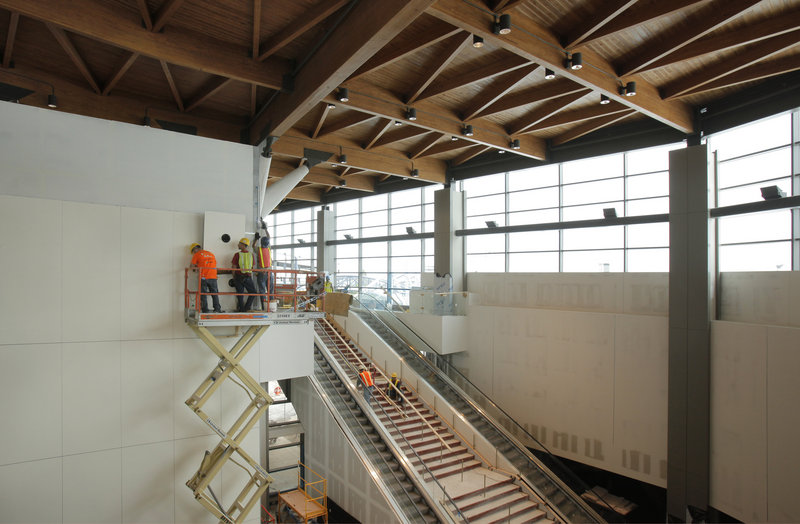 Workers install wall panels Wednesday inside the expanded terminal at the Portland International Jetport. The new facility goes “live” at 4 a.m. on Oct. 2.