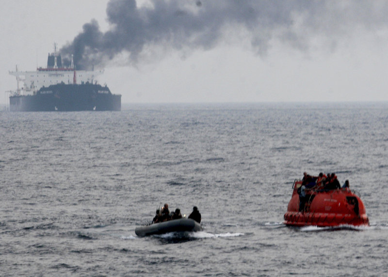 Sailors from the USS Philippine Sea approach a lifeboat, right, to rescue crew members from the Brillante Virtuoso last month in the Gulf of Aden. The tanker is burning in the background.