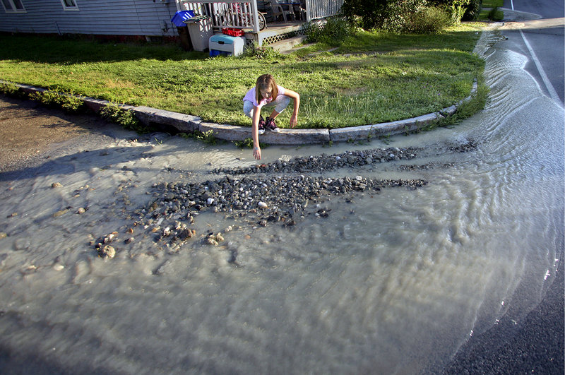 Caitlin Dirocco, 9, of Portland picks through rocks and clay in front of her house that had traveled from a water main break a couple blocks away, at the intersection of Washington Avenue and West Kidder Street, on Thursday.