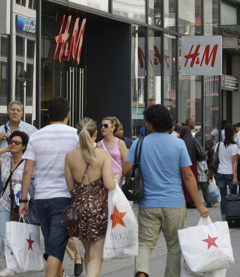 Shoppers carry purchases past H&M in New York. Consumers, who drive most economic growth, spent more on cars and other goods in July – and more in May and June than previously thought.