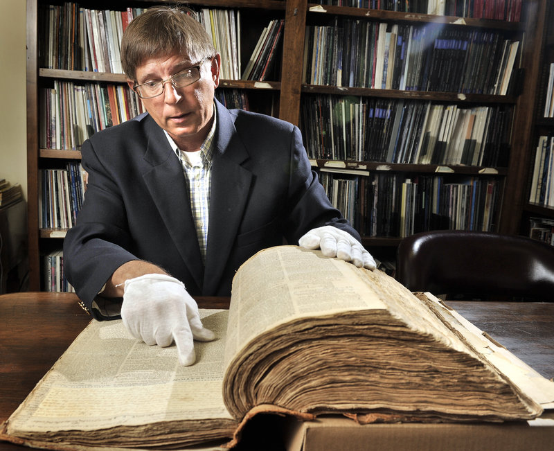 Bill Gage leafs through the pages of an 18th-century newspaper that will be auctioned off later this month. The Bangor Historical Society owns the documents.