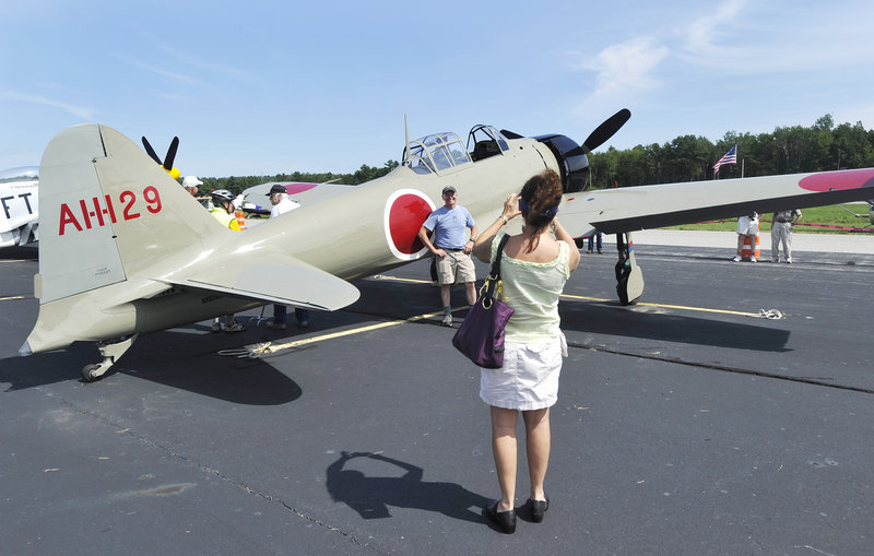 A visitor to the Wiscasset Municipal Airport on Saturday takes a picture of another in front of a Japanese Zero fighter plane. Shortly after 4 p.m., pilots fired up the antique planes and took off. "It's a thrill to hear those big engines," said spectator Jim Thomas, 79.