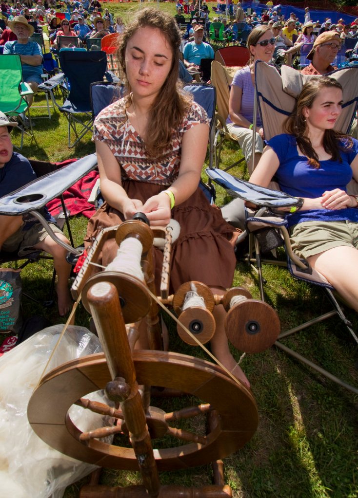 A festival participant spins yarn from wool while listening to music.