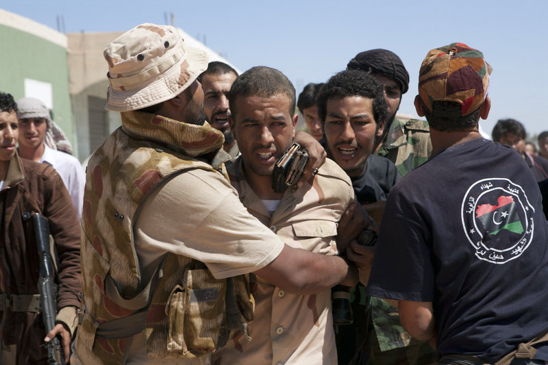 Libyan rebels protect a captured enemy sniper from other rebels near Zawiya, Libya, on Saturday. The prisoner, whose name had not been released yet, was driven away.