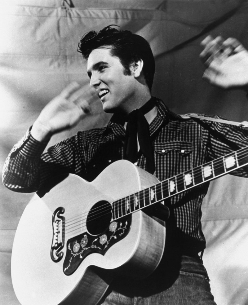 Elvis Presley is shown with his Gibson guitar in 1957. In 1956, 55 years ago, the King released his first two albums, launching his international career.