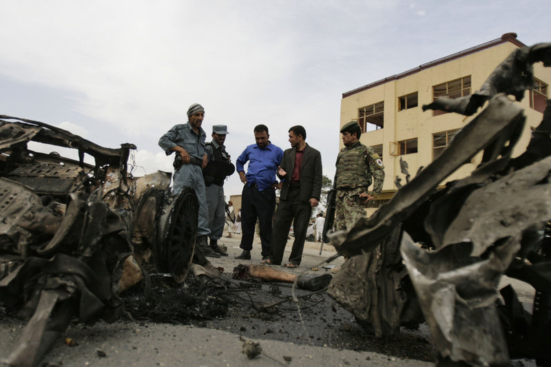 Afghan police officers and soldiers inspect the site of a car bombing Sunday in the Parwan provincial capital of Charikar, some 30 miles north of Kabul, Afghanistan. Sixteen civilian government employees and six police officers were killed.