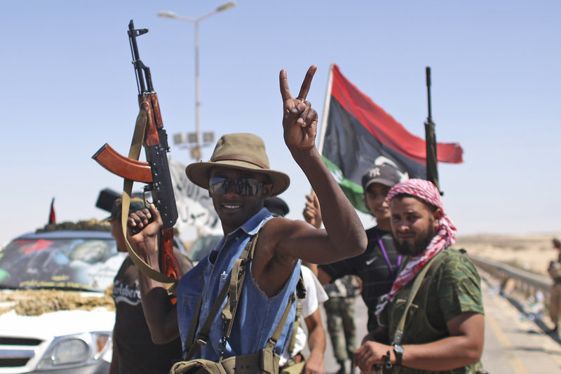 A rebel fighter celebrates Monday at the gates of the town of Brega, Libya. They said most of the town has been liberated from Moammar Gadhafi’s troops. Rebls said they were trying to take refineries in Zawiya, 30 miles from the capital, Tripoli.