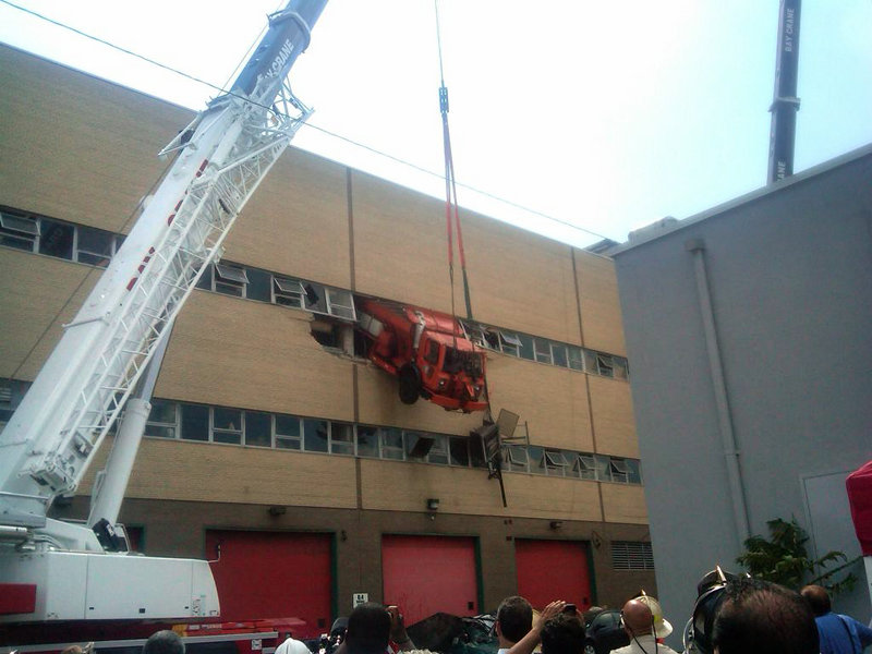 A salt-spreading truck dangles from a building in the New York borough of Queens, suspended from a crane, after it drove through the wall of a repair shop. Firefighters used a cherry-picker to rescue driver Robert Legall, a mechanic who was hospitalized in stable condition.
