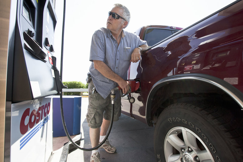 Gary Hartwig of Gretna, Neb., fuels his car at a Costco station in Omaha. Food and gas took a deeper bite out of paychecks last month.