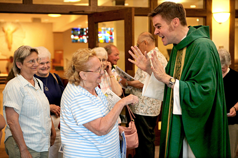 The Rev. Christopher Klusman signs with Lila Dye as he greets parishioners after celebrating Mass in American Sign Language last month at St. Roman Catholic Church in Milwaukee, Wis.