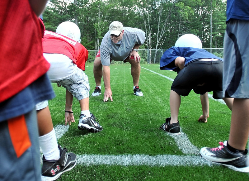 Marty Lyons, a former defensive lineman with the New York Jets in the NFL, demonstrates the proper stance Friday to youngsters at the Camp Tracy Youth Football Camp in Oakland.
