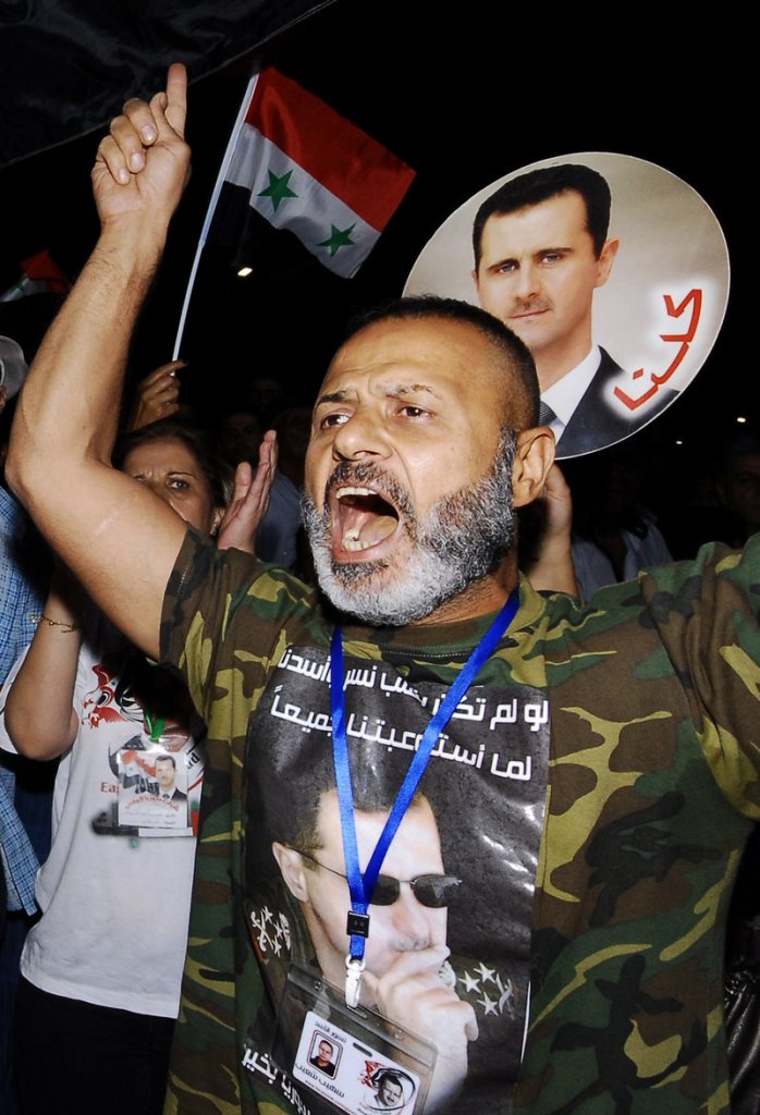 A supporter of Syrian President Bashar Assad, whose portrait is on his T-shirt, demonstrates in Damascus on Friday. Assad, who inherited power from his father in 2000, is facing the most serious international isolation of his rule.