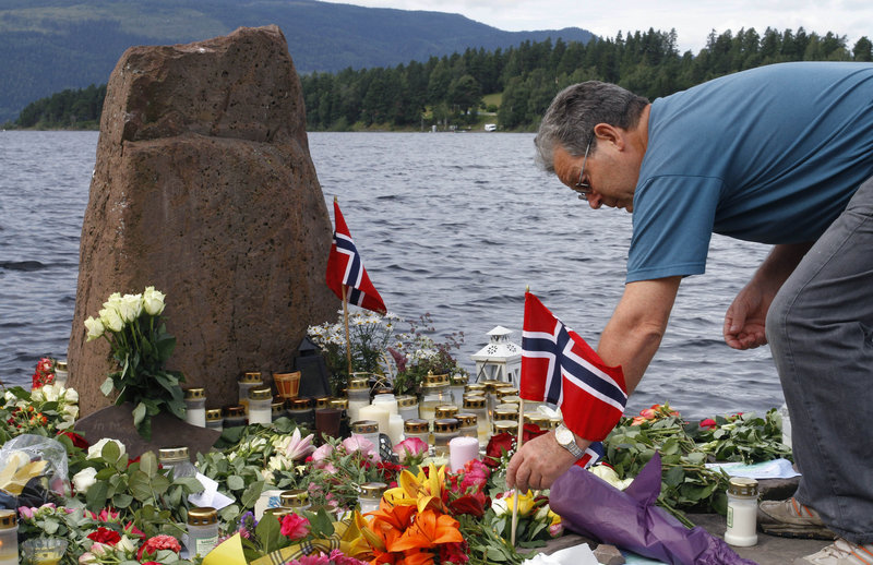 A mourner places a Norwegian flag among flowers on Utoya island, where Anders Behring Breivik killed 69 people last month.