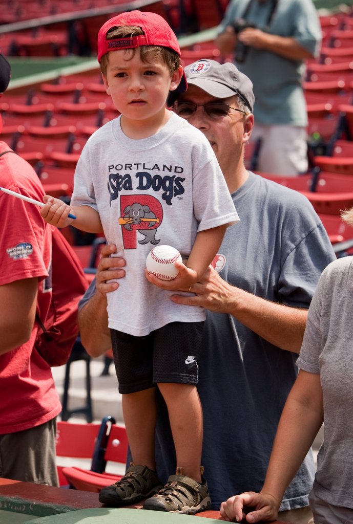 Drew Pulsifer, 4, of Andover, Mass., is held up on the wall by his father, Rich, while seeking autographs before the Sea Dogs game at Fenway Park.