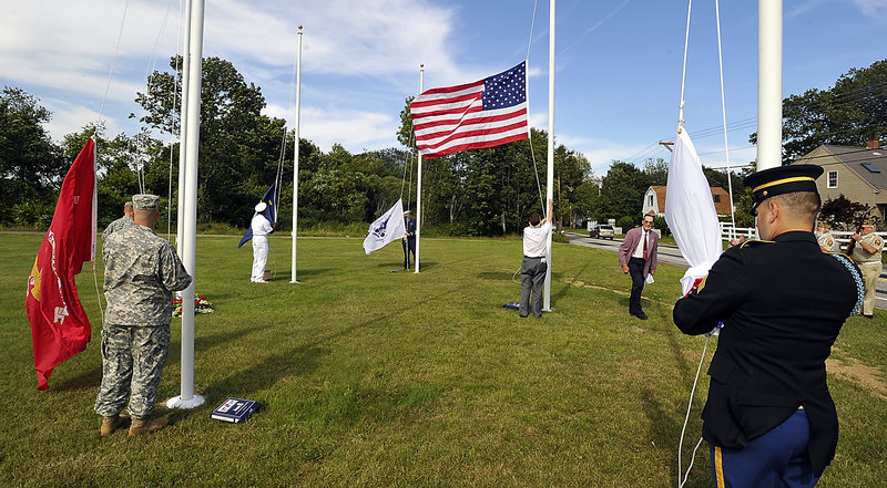 Six flags are raised on new flagpoles Wednesday at Highland Memorial Cemetery in South Portland under the direction of Arthur Smith (in purple sport coat), president of the cemetery, and Don Linscott Jr. of South Portland VFW Post 832, who is raising the American flag. Other flags being raised are, from left, the Marine flag, the Air Force flag, the Navy flag, the Coast Guard flag and the Army flag.