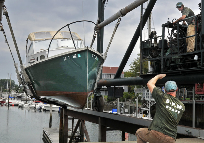 South Port Marine’s Paul Morin directs Adrian Link as they pull boats from Portland Harbor on Thursday.
