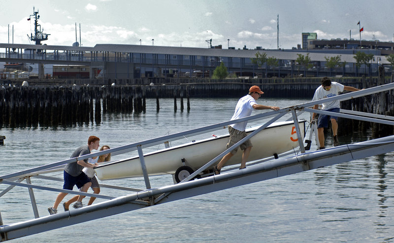 From left, Dylan Bruce, Jessica McGreehan, Doug Baker, and Kyle T. Randall, all of Sail Maine, remove one of Sail Maine's boats from the water on Friday in preparation for Hurricane Irene.