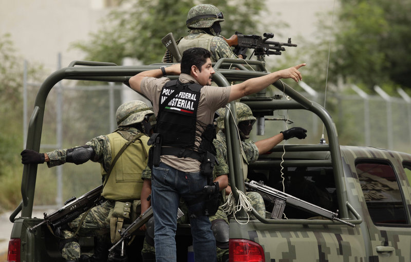 A federal police officer and soldiers patrol Friday near the Casino Royale in Monterrey, Mexico, where 52 civilians died Thursday in a fire believed to have been set by drug gangs.