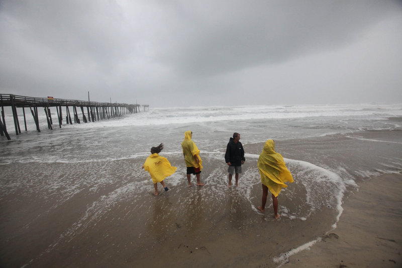 From left, Sophie Waterfield, Skylr Peele, Chloe Waterfield and Tim Waterfield look out at the ocean waves near the Frisco, N.C., pier as the first storm bands from Hurricane Irene arrive Friday. By evening, 50 mph winds were raking the North Carolina coast.