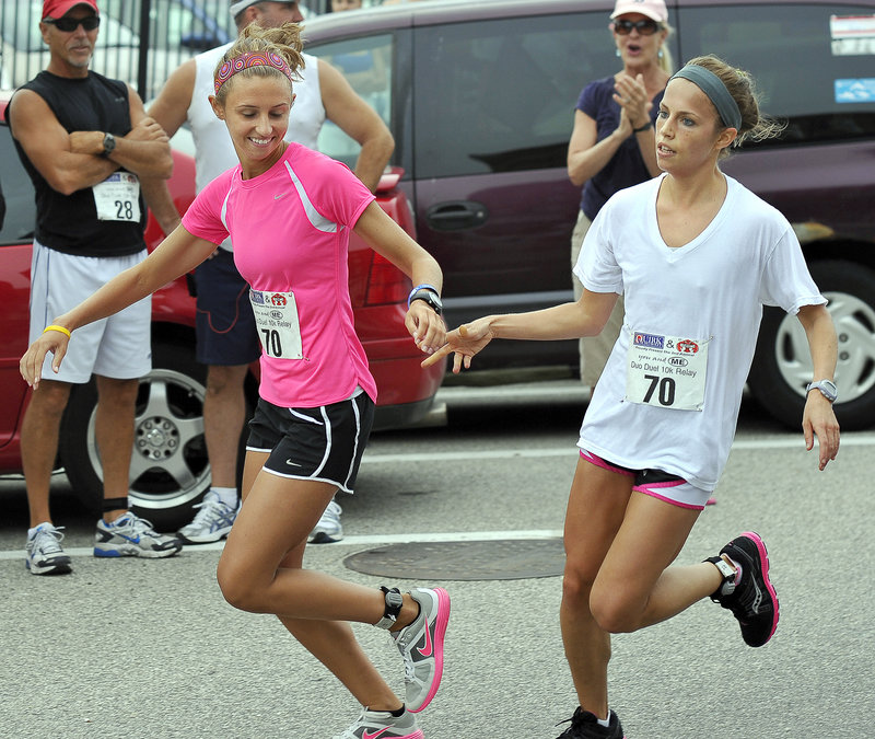 Carly Dion, right, makes the wristband exchange with Erin Garvey and sends her on her way to complete the second 5-kilometer leg of the race.