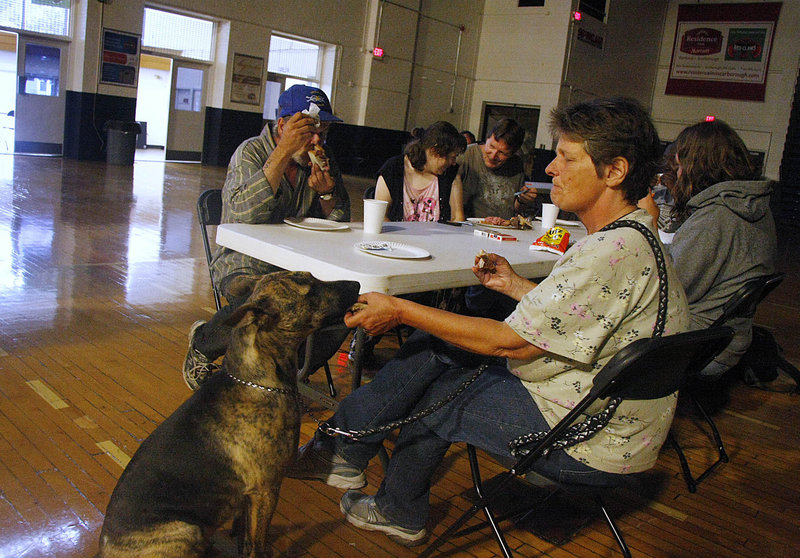 Patricia Steffens of Portland shares a bite of her sandwich with her dog, Sadie, while spending the day at the shelter at the Portland Expo on Sunday during Tropical Storm Irene.