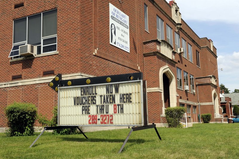 A sign at Our Lady of Hungary Catholic School in South Bend, Ind., encourages students to enroll using school vouchers. It’s a scenario that public school advocates have long feared.