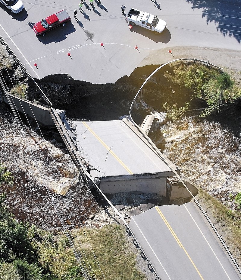 Gov. Paul LePage and other officials survey one of two washed-out bridges Monday on Route 27 in Carrabassett Valley. The damage temporarily cut off access to Sugarloaf Mountain.