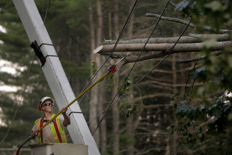 Nick Constantakos uses a saw to remove branches Tuesday from a tree that had fallen on power lines along Chadbourne Ridge Road in Waterboro. Constantakos works for Lewis Tree Service, which contracts with Central Maine Power for tree trimming and removal.