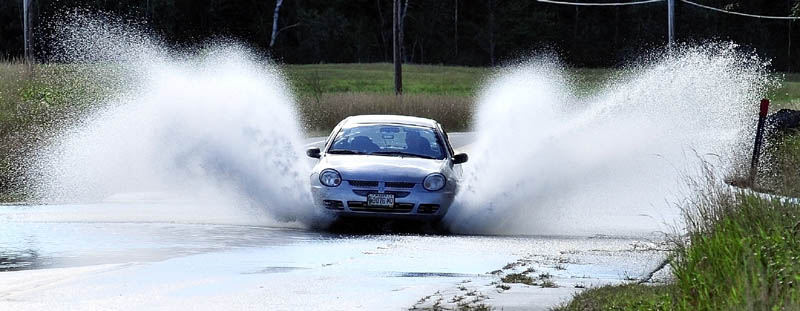 TROPICAL SPRAY: A motorist on Monday blasts through water where Route 16 in Embden is flooded from rain from Tropical Storm Irene.
