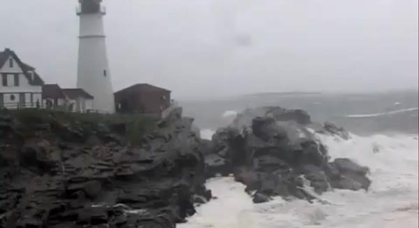 Waves break over the rocks below the keepers quarters at Portland Head Light.