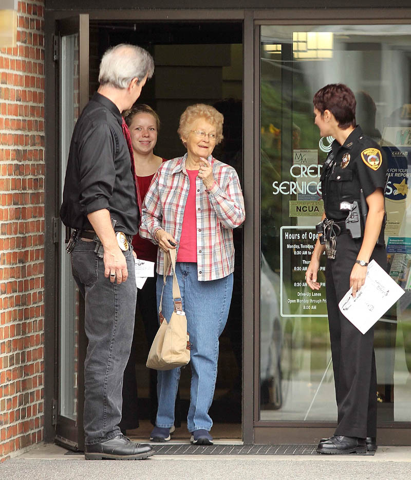 LEAVING UNHARMED: Winslow Police Chief Jeffrey Fenlason and officer Linda Smedberg let customers out of the Winslow Community Federal Credit Union on Monument Street after it was robbed Thursday morning. The robbery occurred around 9:50 a.m.