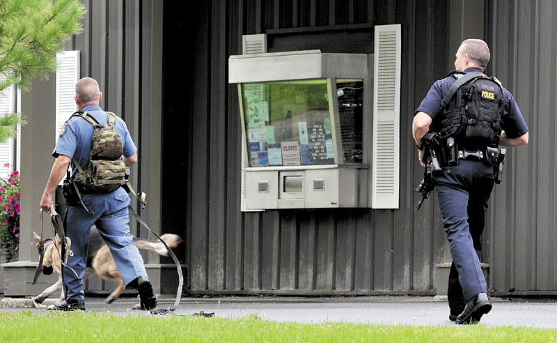 SEARCH: A Maine state trooper with a tracking dog and Waterville police Sgt. Dan Ames search outside HealthFirst Federal Credit Union in Waterville on Thursday after a male reportedly armed with a knife robbed the credit union.