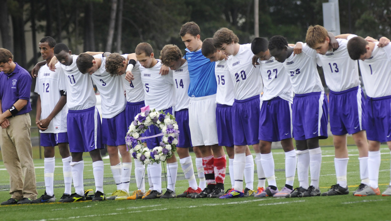 Deering High School’s soccer team stands together during a moment of silence in memory of their teammate, 17-year-old senior Mohamed Hassan, who drowned Saturday while swimming with friends in the Presumpscot River off Allen Avenue Extension in Falmouth. The remembrance took place at Deering’s game Thursday against Noble High School in Portland. The wreath was a gift from the Noble team.