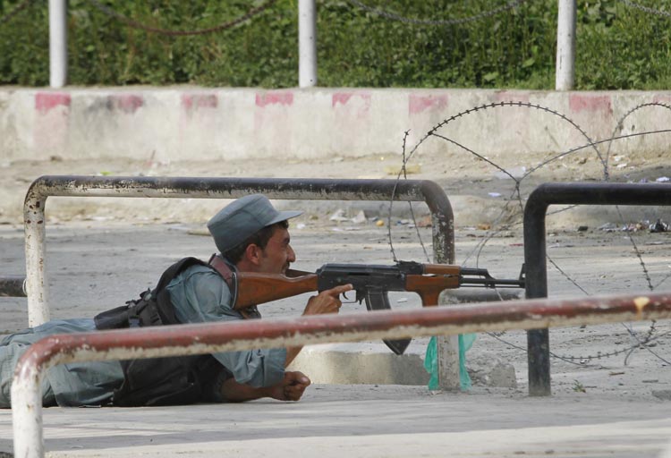 An Afghan policeman takes position near the building occupied by militants, unseen, in Kabul, Afghanistan today.
