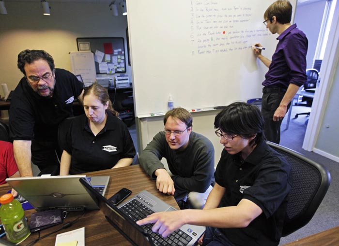 Aspiritech co-founder Moshe Weitzberg, standing left, works with employees – seated from left, Katie Levin, Rick Alexander and Jamie Specht, as they test a new program in Highland Park, Ill.