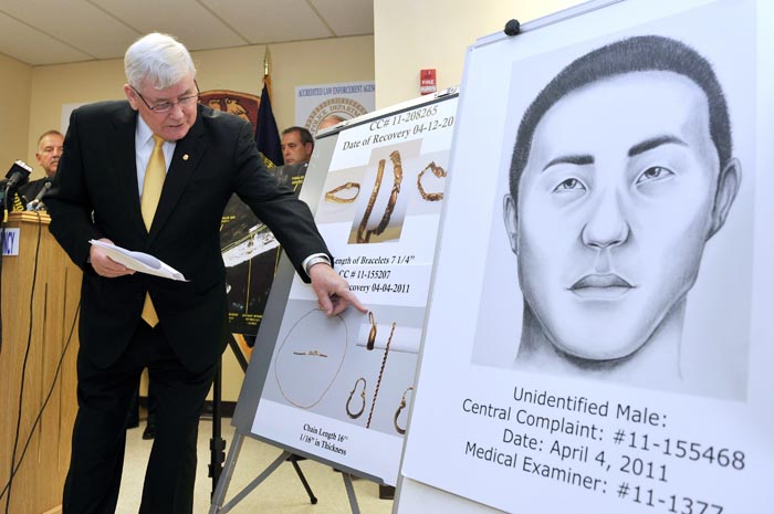 Suffolk County Police Commissioner Richard Dormer points out photographs of jewelry recovered from bodies found along Ocean Parkway in Suffolk County at a news conference today in Yaphank, N.Y. At right is a drawing of an unidentified male body found.