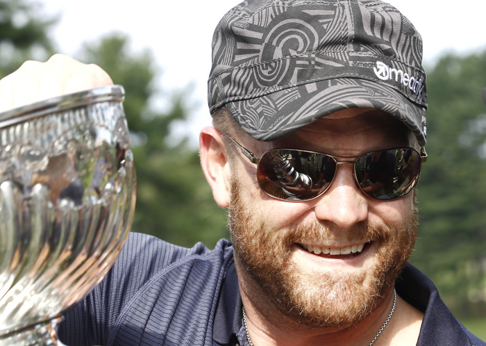 Boston Bruins goaltender Tim Thomas carries the Stanley Cup during a golf tournament in Bolton, Mass., recently.