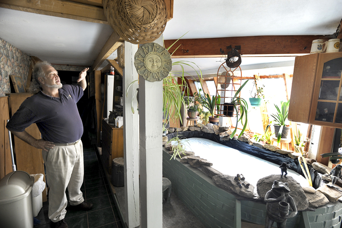 Michael Mayhew points out details in his greenhouse attached to his kitchen.