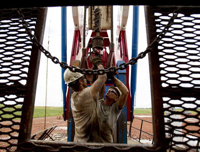 Austin Mitchell, left, and Ryan Lehto, work on an oil derrick outside of Williston, N.D. With what many are calling the largest oil boom in recent North American history, temporary housing for the huge influx of workers, known as "man camps," now dots the sparse North Dakota landscape.