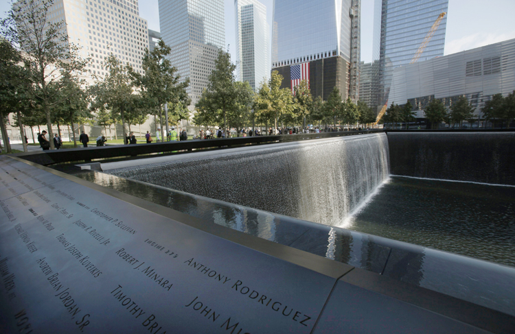 Visitors stroll the grounds near one of the pools at the 9/11 memorial plaza in the World Trade Center site in New York today.