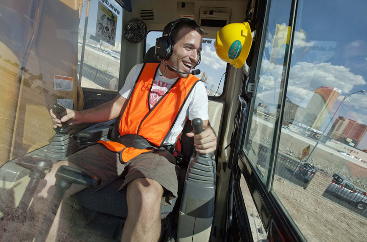 Grayson Cox, of Austin, Texas, works the controls of an excavator while learning to use construction equipment at Dig This in Las Vegas. For a few hundred dollars, tourists spend a few hours at Dig This pushing around dirt, one-ton tires and rocks that don't move when you kick them.