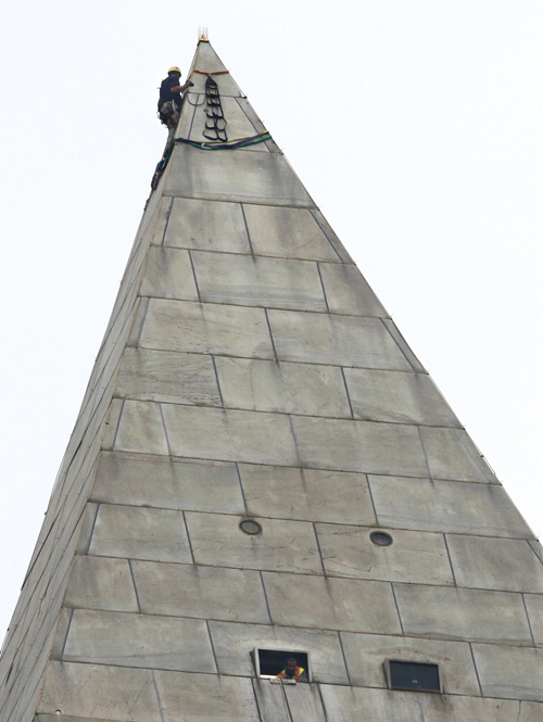 A man attaches rigging to the top of the Washington Monument on the National Mall today, before engineers rappeled down the sides of the monument to survey the extent of damage from the Aug. 23 earthquake.