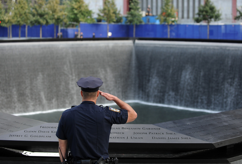 A New York City police officer salutes at the north pool of the Sept. 11 memorial as the national anthem is sung during the 10th anniversary ceremonies at the World Trade Center today in New York.